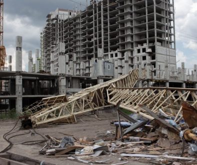 Construction site featuring a collapsed crane and unfinished buildings under cloudy skies.
